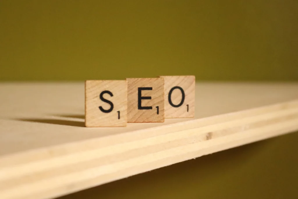 Wooden Scarbble pieces on a plywood table spelling SEO for Search Engine Optimization.